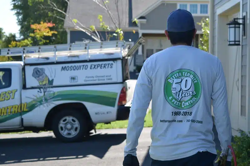 Pest control technician walking outside home