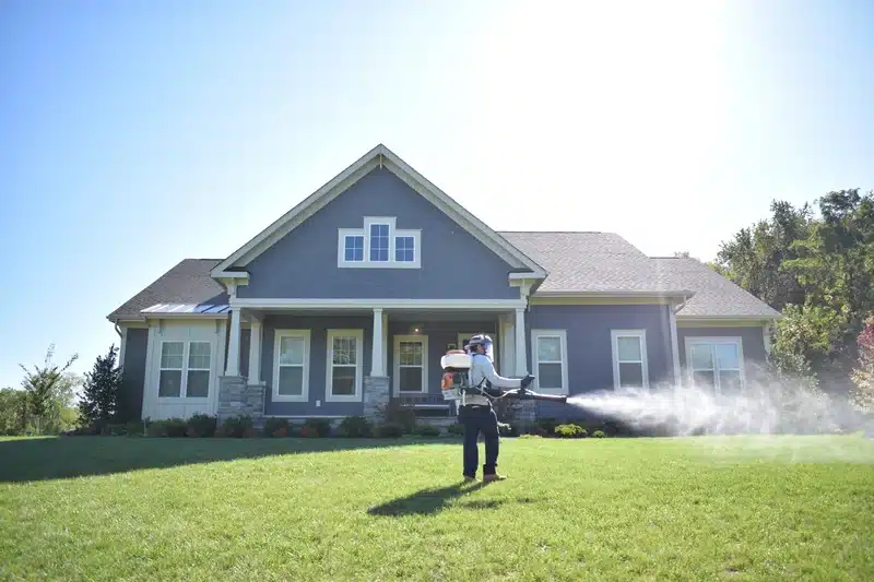 Technician treating exterior areas of home for comprehensive flea control